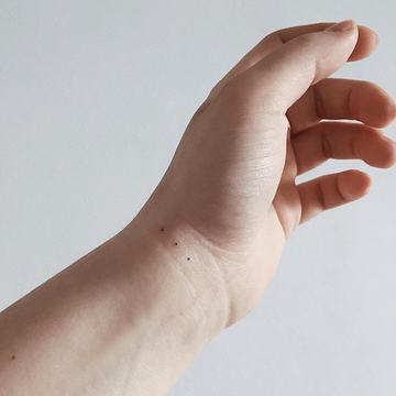 Drobny tatuaż z kropką na dłoni