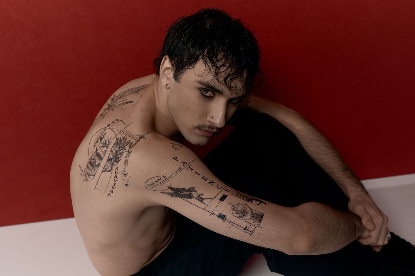 Kompozycja czarnych tatuaży różnej skali na ramieniu.