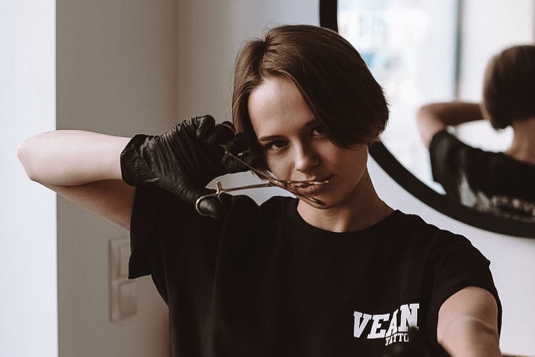 Piercer w rękawiczkach trzyma narzędzie do piercingu