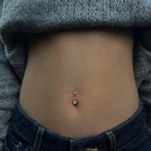 Piercing pępka subtelnie podkreśla brzuch. Delikatna biżuteria tworzy estetyczny efekt.