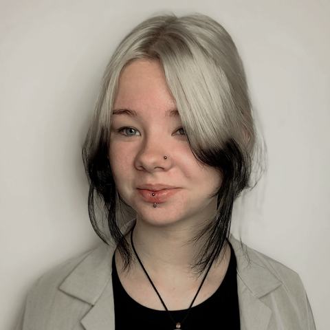Podwójny piercing dolnej wargi podkreśla uśmiech. Drobna biżuteria nadaje stylizacji delikatny akcent.