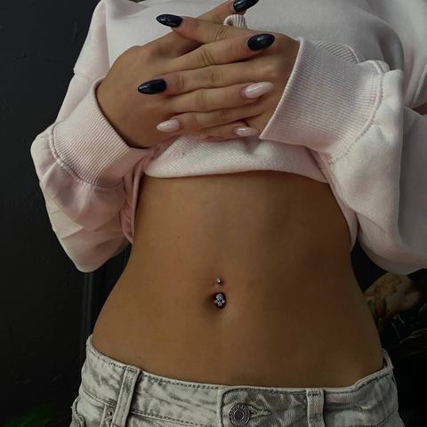 Piercing pępka delikatnie podkreśla brzuch. Klasyczna biżuteria tworzy subtelny efekt.