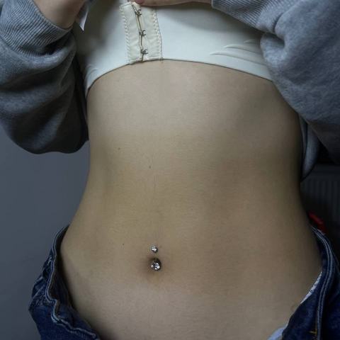 Piercing pępka delikatnie podkreśla sylwetkę. Drobna biżuteria nadaje całości subtelny charakter.