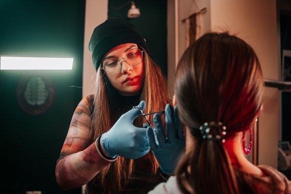 Piercer w rękawiczkach przekłuwa ucho w Częstochowie
