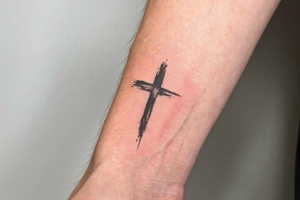 Tatuaż z czarnym krzyżem na przedramieniu
