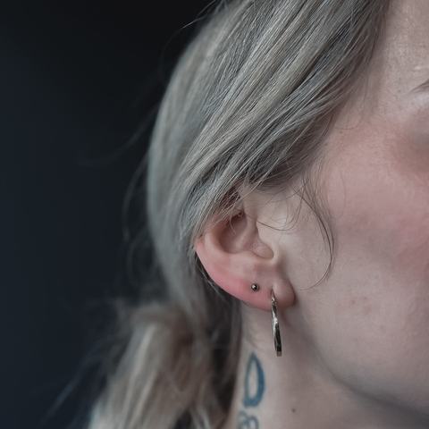 Piercing ucha delikatnie podkreśla profil. Drobna biżuteria dodaje stylizacji subtelnego blasku.