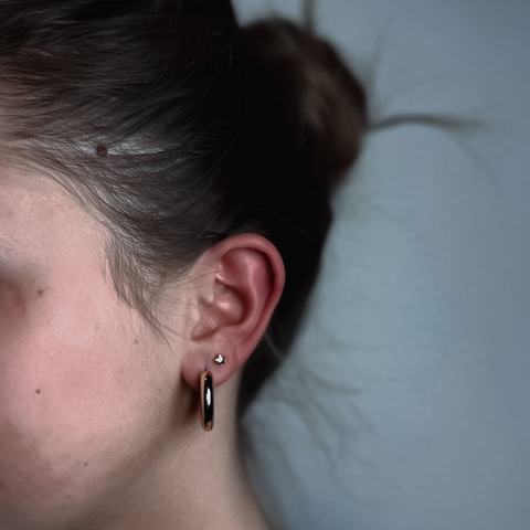 Piercing ucha subtelnie podkreśla profil. Srebrne kółko dodaje stylizacji wyrazistego akcentu.
