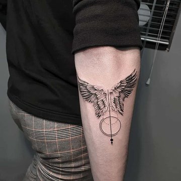 Tatuaż skrzydeł na przedramieniu z okrągłym detalem