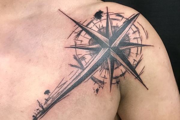 Tatuaż róży wiatrów na barku z graficznymi liniami