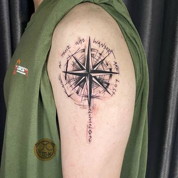 Tatuaż róży wiatrów na ramieniu z delikatnymi napisami