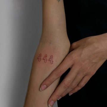 Czerwony tatuaż 444 na przedramieniu