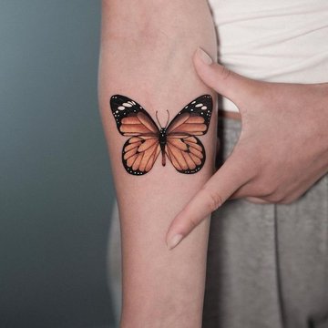 Mały kolorowy tatuaż motyla na nodze