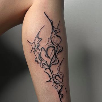 Tribalowy tatuaż na łydce z cienkimi, wijącymi się liniami