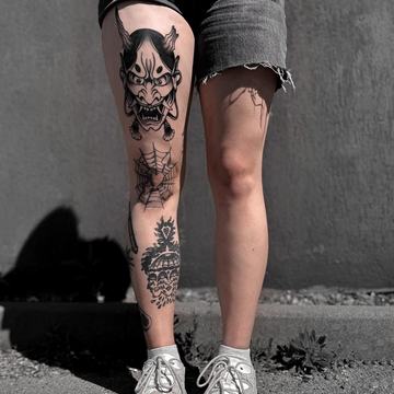 Kompozycja czarnych tatuaży na nodze, różna skala