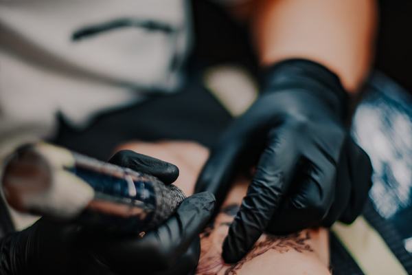 Tatuaż w sterylnych rękawiczkach na przedramieniu