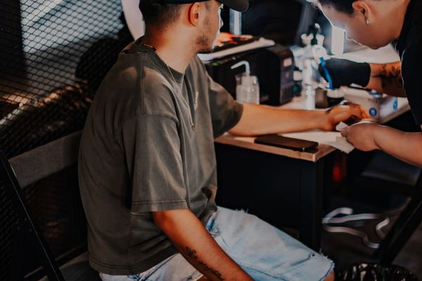 Tatuażysta w rękawiczkach tatuuje ramię klienta