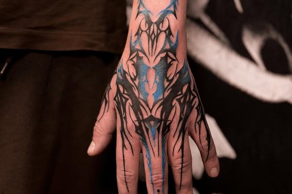 Widoczny tatuaż na dłoni: czarno-niebieski ornament