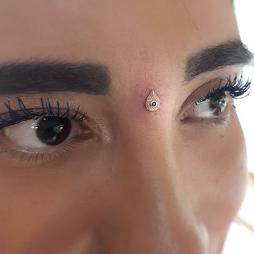 Piercing microdermal na czole, łezka między brwiami
